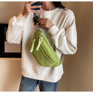Detail of green nylon crossbody bag with embroidered strap and woven zipper pullers