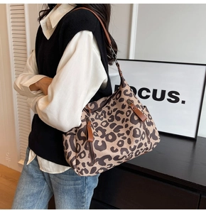 Detail of leopard print canvas shoulder bag featuring brown leather strap and side zipper