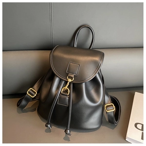 Détail d'un sac à dos en cuir noir avec boucle dorée sur un canapé minimaliste