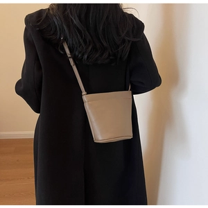 Vue détaillée d'un sac seau en cuir kaki avec fine bandoulière porté par un mannequin