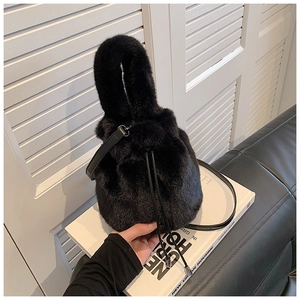 Détail du sac seau en fausse fourrure noire avec cordon en cuir et texture pelucheuse