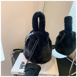 Détail d'un sac seau noir en fausse fourrure avec poignée et bandoulière en cuir