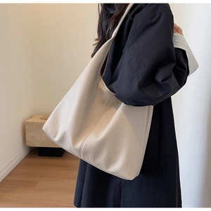 Detail of off-white lychee pattern leather tote bag shown on a model's shoulder
