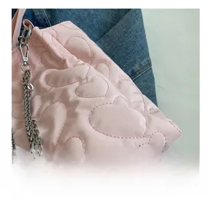 Détail d'un sac en nylon rose clair matelassé avec motifs de cœurs et chaîne argentée