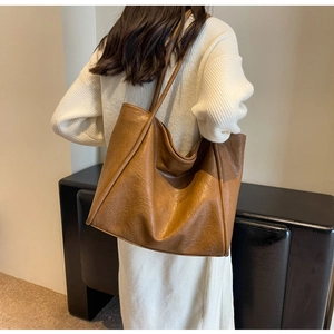 Brown faux leather tote bag showing textured surface and slender shoulder straps