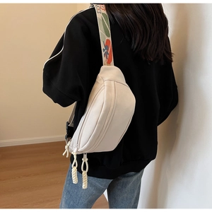 Detail of ivory crescent crossbody bag with floral strap and knotted zipper pulls