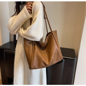 Detail shot of the vintage wrinkled leather texture on a caramel brown tote bag