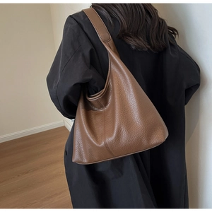 Detail of dark brown pebbled leather hobo bag with seamless strap on a model's shoulder