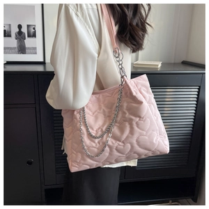 Vue détaillée du sac cabas en nylon rose matelassé avec chaîne argentée sur l'épaule du mannequin