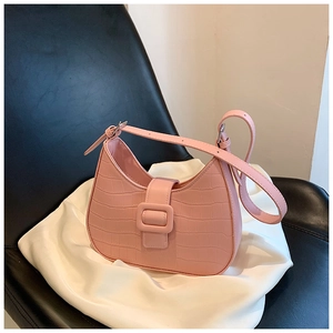Detailed view of pink croc-embossed hobo bag with resin buckle on white fabric