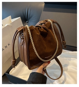 Detail of vintage brown suede bucket bag with gold chain and refined white stitching