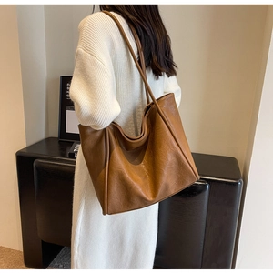 Close-up of a large dark brown leather tote bag with fine texture and dual shoulder straps