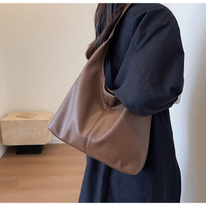 Detail of coffee brown hobo bag with litchi grain leather texture and stitching