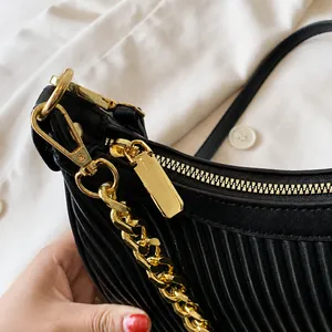 Détails de la quincaillerie dorée et texture plissée noire sur un sac à bandoulière