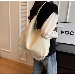 Model wearing large off-white hobo tote bag with pebble leather texture and wide strap