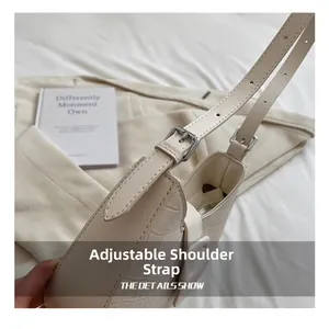 Detail of adjustable shoulder strap with silver buckle on cream crocodile embossed bag