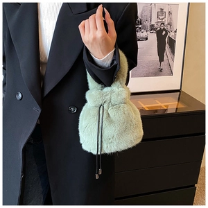 Détail du sac seau en fausse fourrure vert clair avec cordons noirs et peluche douce