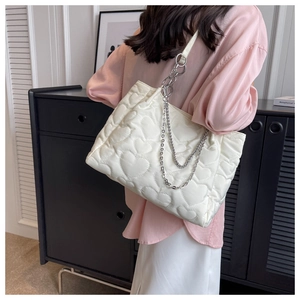 Détail du motif matelassé en cœur et de la chaîne argentée sur le sac fourre-tout blanc