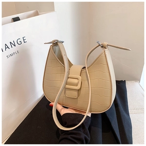 Detail of beige crocodile pattern underarm bag with decorative buckle and PU leather texture