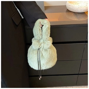 Détail d'un sac seau en fausse fourrure vert clair avec cordon de serrage et texture douce