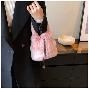 Détail du sac seau en fausse fourrure rose avec texture douce et cordon à embouts en métal