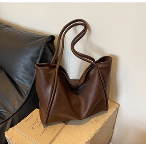 Close-up of brown faux leather tote bag with fine texture on a stone pedestal