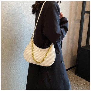 Sac hobo beige plissé avec bandoulière en chaîne dorée porté par un mannequin