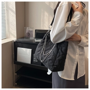 Détail du sac cabas en nylon matelassé noir avec motif cœur et bandoulière chaîne