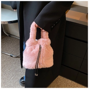 Détail du sac seau en fausse fourrure rose avec cordon noir et texture moelleuse