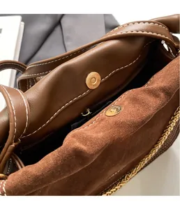 Close-up of brown leather bucket bag featuring gold snap buttons and chain details