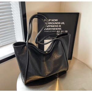 Macro view of textured black leather tote bag with elegant long shoulder straps