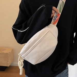 Minimalist beige half-moon canvas chest bag with colorful geometric patterned jacquard strap