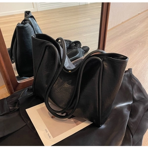Detailed view of black soft leather tote bag with unique wave-layered handle design