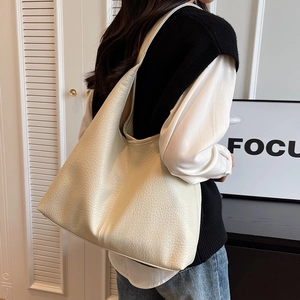 Chic beige pebbled leather Hobo bag shown on shoulder in a minimalist interior setting