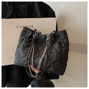 Gros plan sur un sac fourre-tout en nylon noir avec matelassage cœur et chaîne argentée