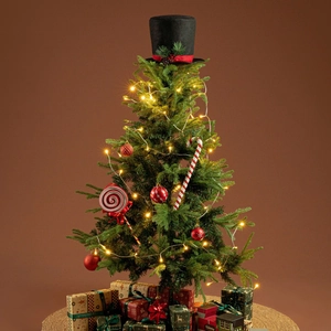 Detailed view of a Christmas tree topper featuring a black top hat with red ribbon and pine cones