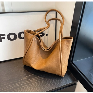 Detail of caramel brown large tote bag with soft leather texture and slender straps