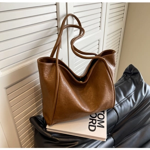 Close-up of caramel leather tote bag with vintage wrinkled texture on a black sofa
