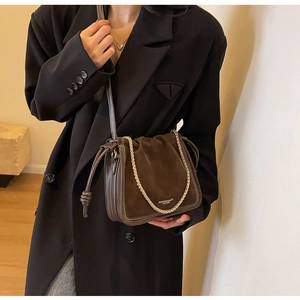 Detail of dark brown leather bucket bag with gold chain and vintage drawstring design
