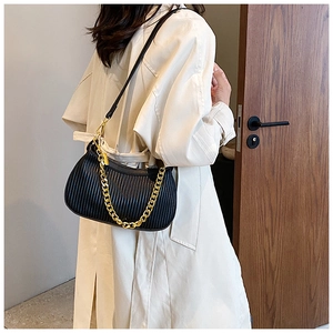 Détail du sac croissant plissé noir avec chaîne dorée porté par le mannequin