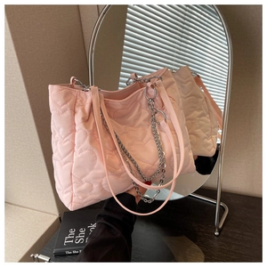 Détail du cabas en nylon rose matelassé en cœurs avec une grosse chaîne en métal argenté
