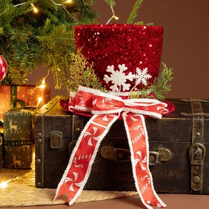 Close-up of a festive red sequin Christmas tree topper hat with ribbons and snowflakes