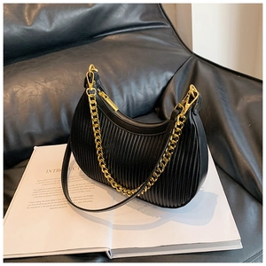 Gros plan détaillé du sac croissant plissé noir avec chaîne dorée sur canapé cuir