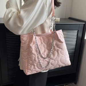 Grand sac cabas en nylon matelassé rose avec chaîne en argent porté par le modèle