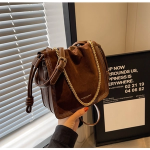 Detail of vintage brown suede bucket bag with gold chain and knot accent on side