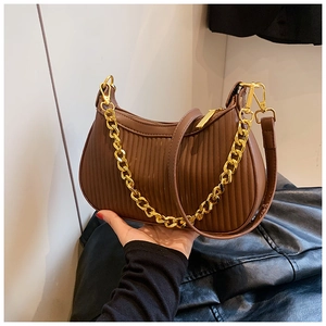 Détail du sac croissant marron froncé avec chaîne dorée et plis verticaux