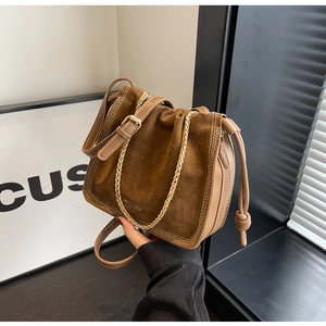 Detail of brown vintage bucket bag featuring suede panels and decorative stitching