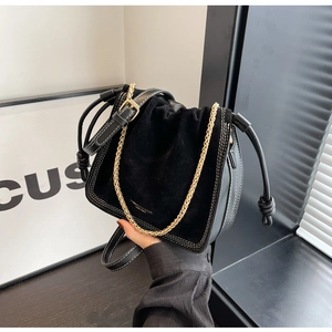 Detail of black drawstring bucket bag with gold chain and matte suede texture finish