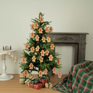Set of 26 gingerbread man alphabet ornaments hanging on a Christmas tree in a cozy home