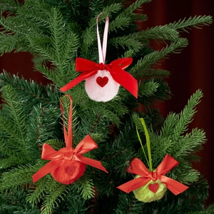 Nahaufnahme von rosa und grünen Plüsch-Weihnachtskugeln mit roten Schleifen am Baum